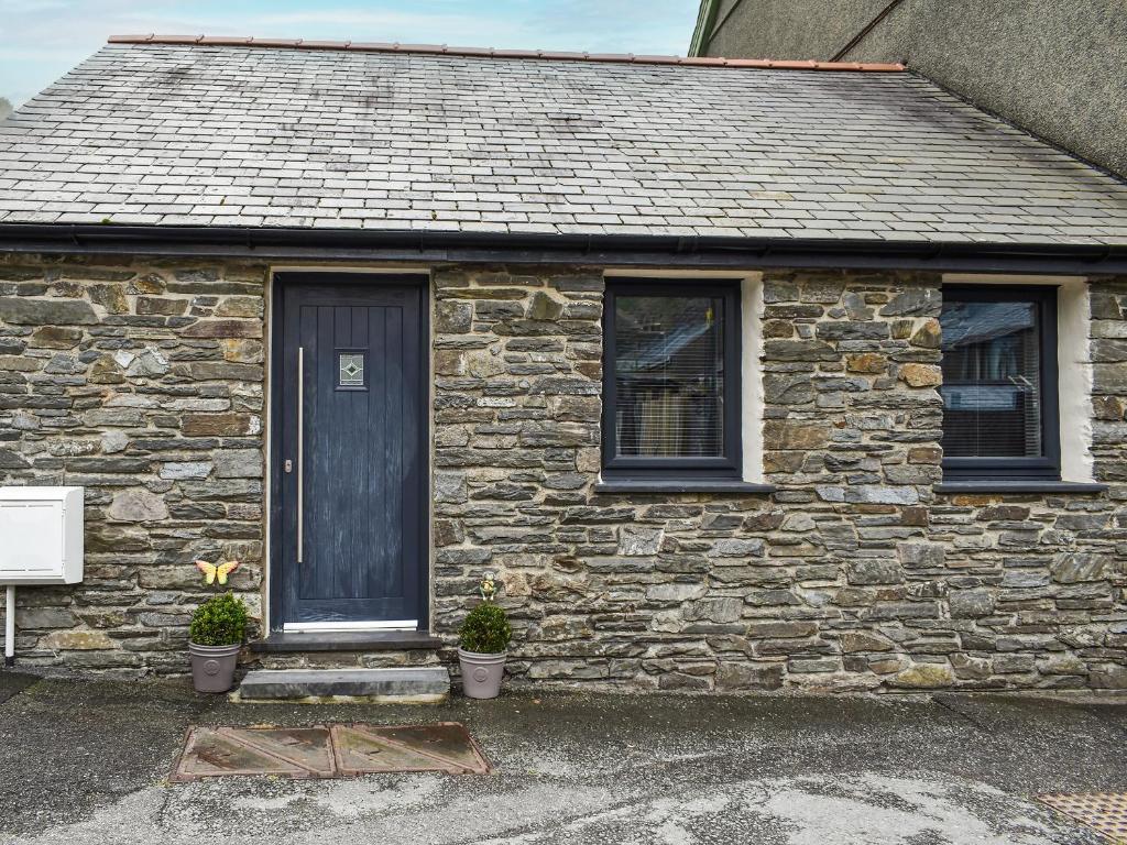 a stone house with a blue door and two windows at Seion Villa in Blaenau-Ffestiniog