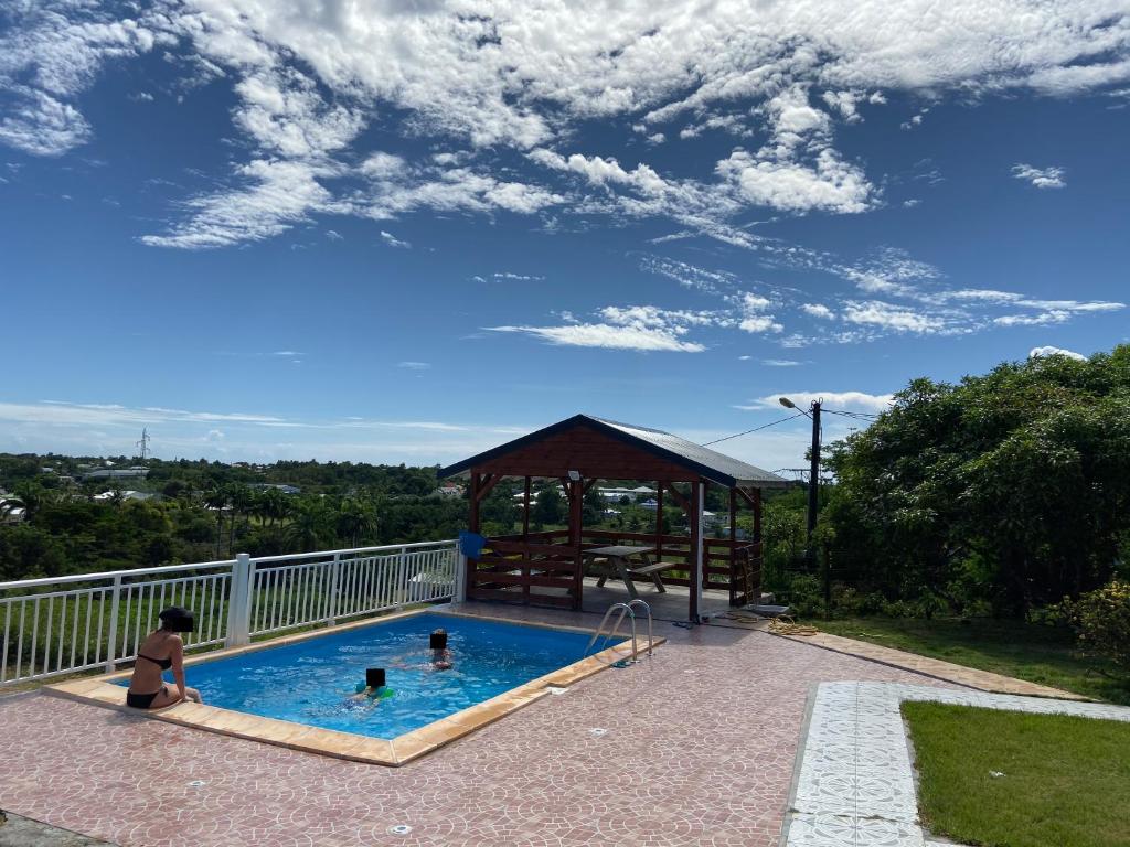 ein Swimmingpool mit einem Pavillon und einem Kind darin in der Unterkunft Gîte Allée des Cocotiers in Saint-François