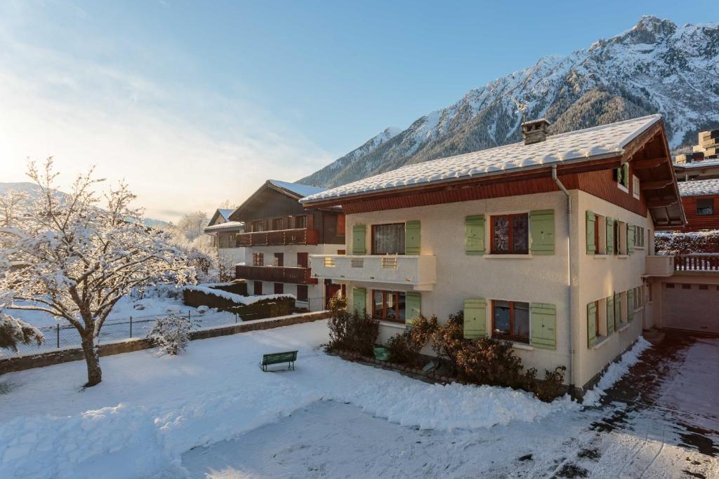 a house in the snow with mountains in the background at Edelweiss apartment - Chamonix All Year in Chamonix