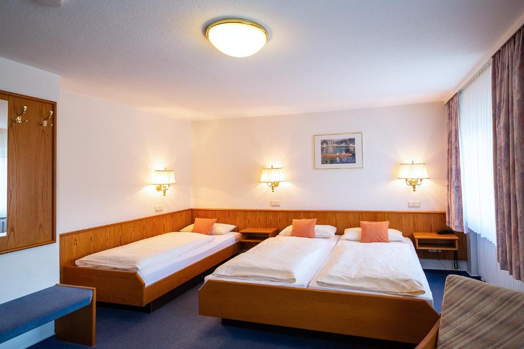Hotel Am Steinberg في هيلدسهايم: سريرين في غرفة بطاولتين
