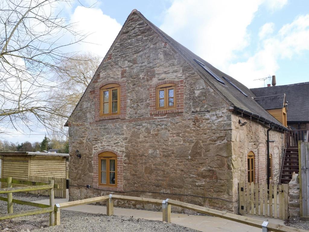 an old stone house with yellow windows on the side at No, 2 Ash Cottage in Quatt