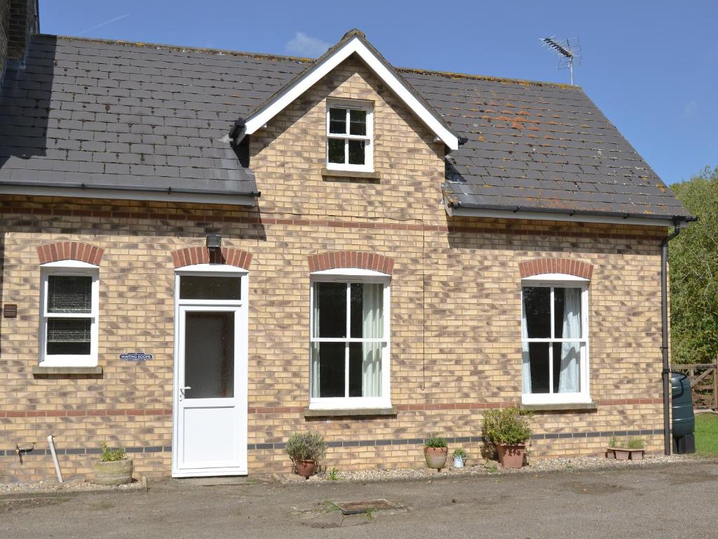 a brick house with a white door and windows at The Waiting Rooms in Cawston