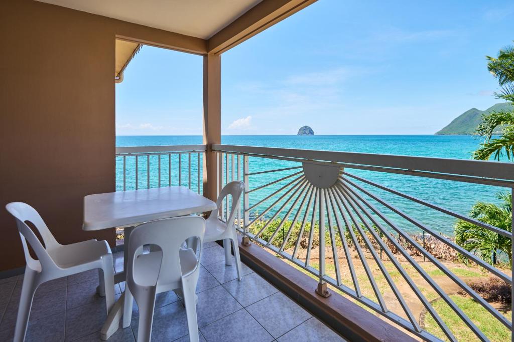 balcón con mesa, sillas y vistas al océano en Diamant Beach, en Le Diamant