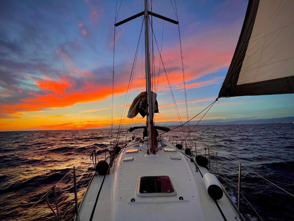 una barca nell'oceano con un tramonto sullo sfondo di Precioso velero en Badalona de 3 camarotes a Badalona