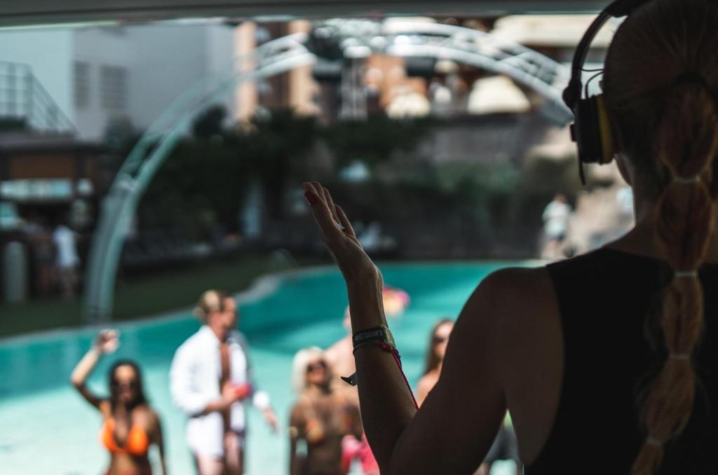 a woman standing in front of a group of people at a pool at BC Music Resort in Benidorm