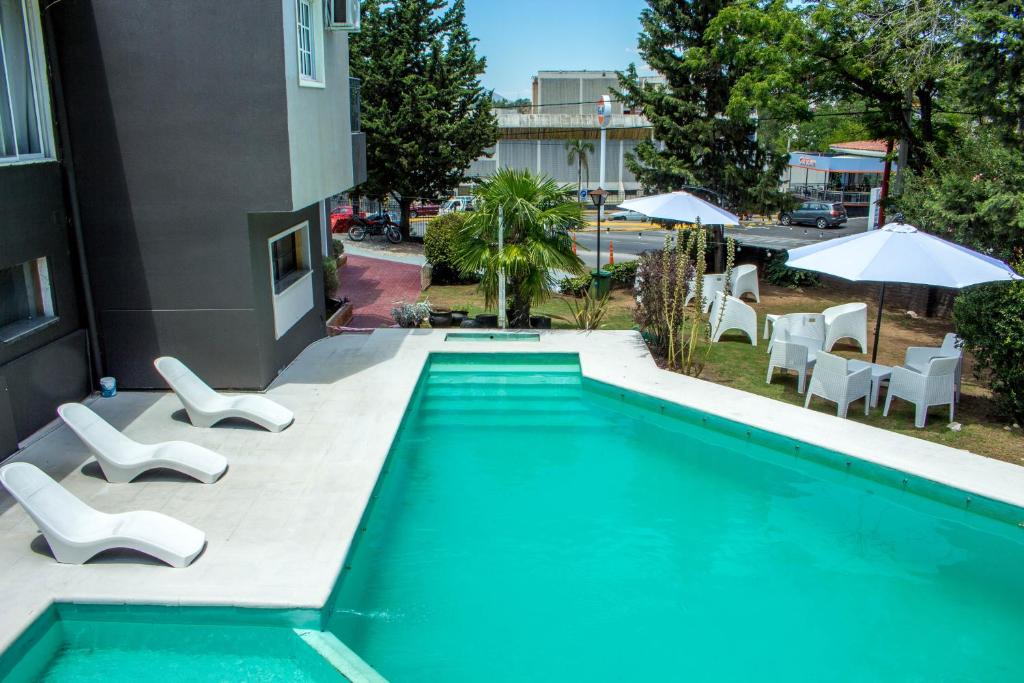 una piscina con sillas blancas y un edificio en Hotel Terrazas by CPH en Villa Carlos Paz