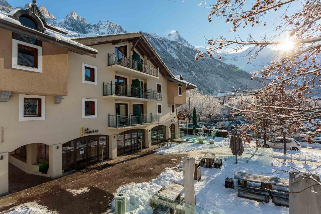 un grande edificio con neve sul terreno e sulle montagne di Ginabelle 8 apartment - Chamonix All Year a Chamonix-Mont-Blanc