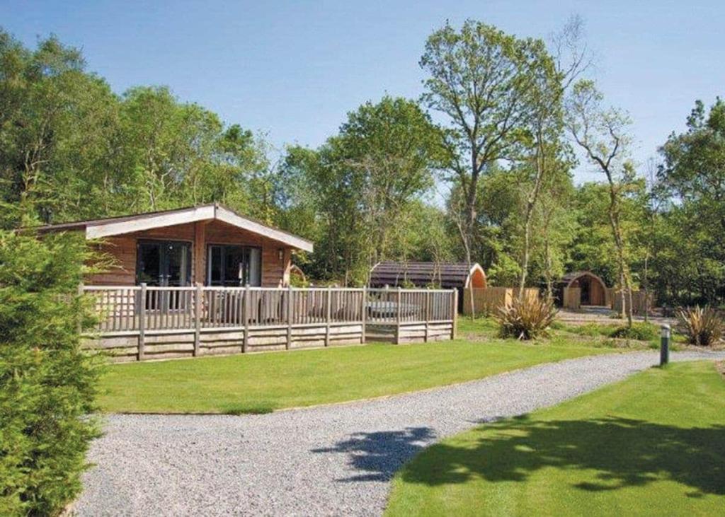 a cabin with a fence and a gravel driveway at Woodthorpe Leisure Park in Strubby