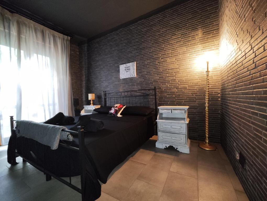 1 dormitorio con cama y pared de ladrillo en Hotel Transilvania, en Pian del Voglio