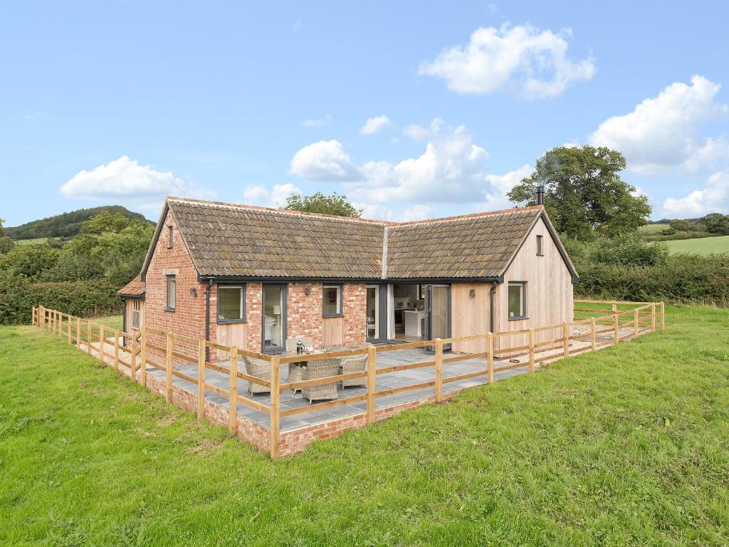a house with a wooden deck in a field at The Old Piggery in Sidbury