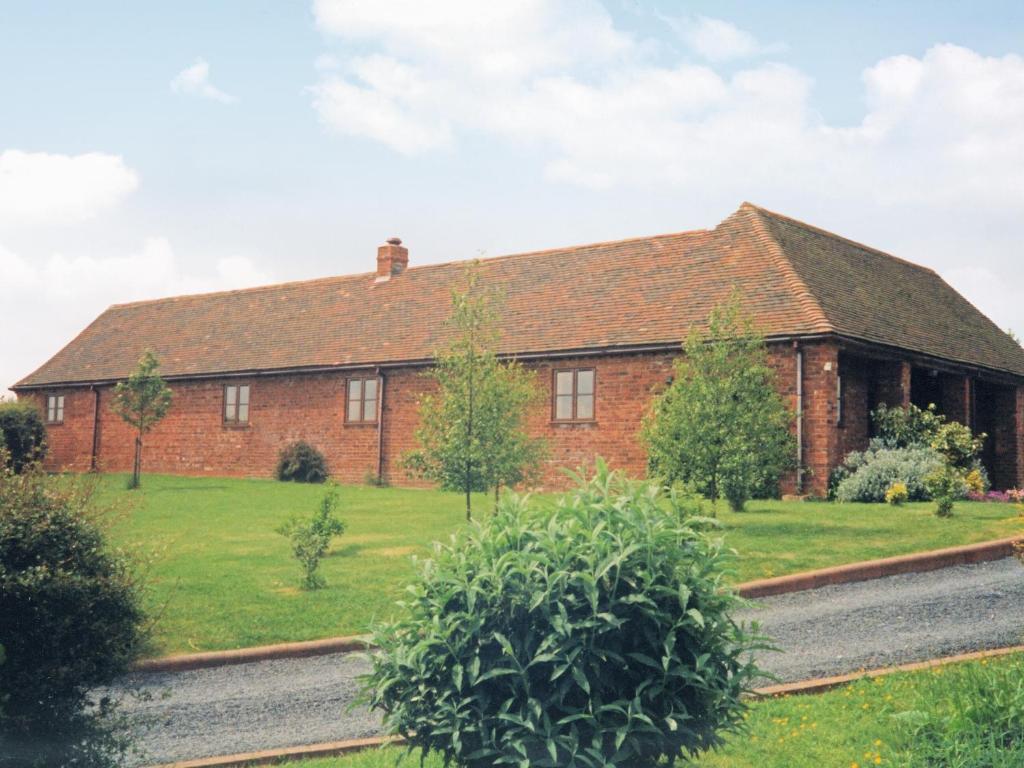 a large red brick house with a green yard at Stildon Manor Cottage in Pensax