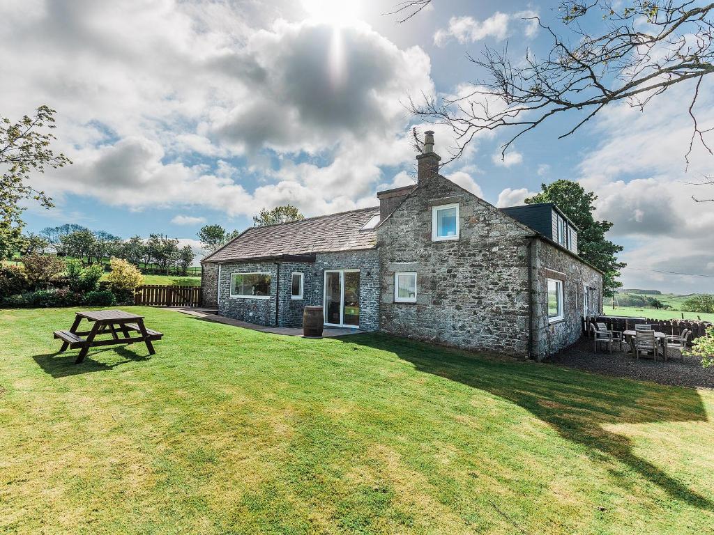 a stone house with a picnic table in the yard at Robins Nest in Kirkcudbright