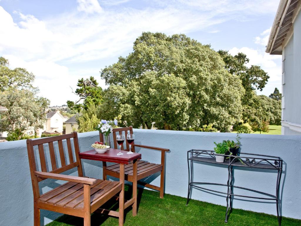a patio with two chairs and a table on the grass at Courts View in Newton Abbot