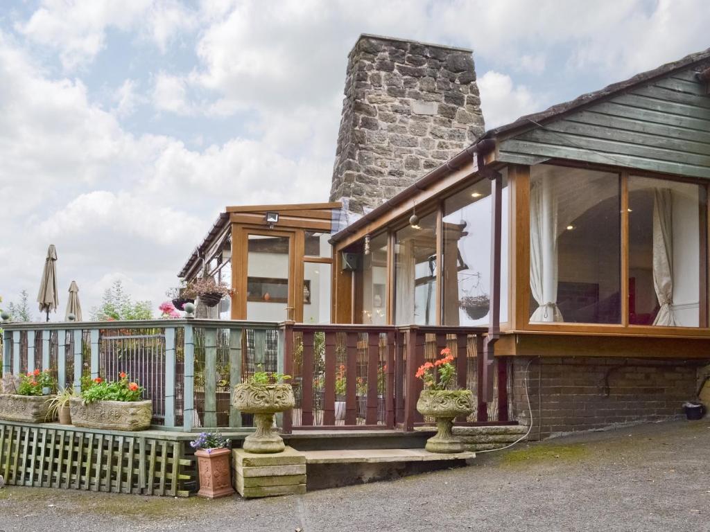 a house with a balcony with flowers in pots at Woodend Bungalow in Hucknall under Huthwaite