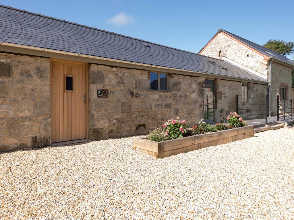 un granero de piedra con una puerta y flores en un patio en Property 2 en Wroxall