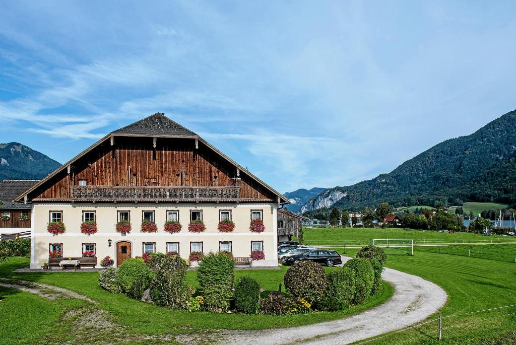 ein großes weißes Gebäude mit einem Holzdach in der Unterkunft Plombergbauer in Sankt Gilgen