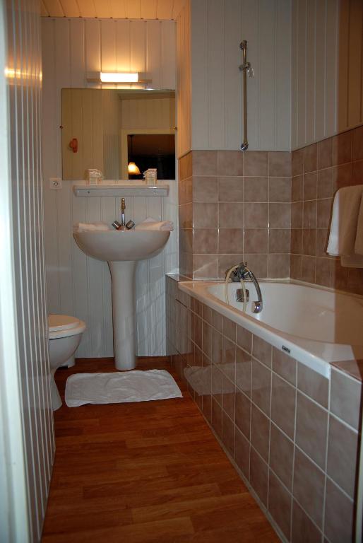 a bathroom with a sink and a tub and a toilet at Hotel De France in Pontorson