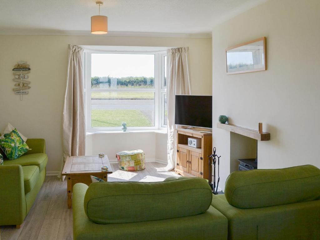 a living room with two green couches and a window at Valley View in Morwenstow