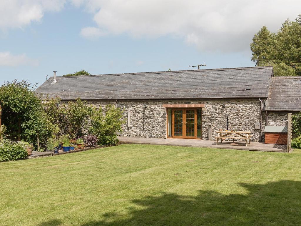 a stone cottage with a large lawn in front of it at Yr Hen Stabl in Tregaron