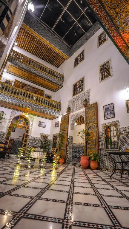 una hall di un edificio con una sala con soffitti decorati di Riad Green House a Fes