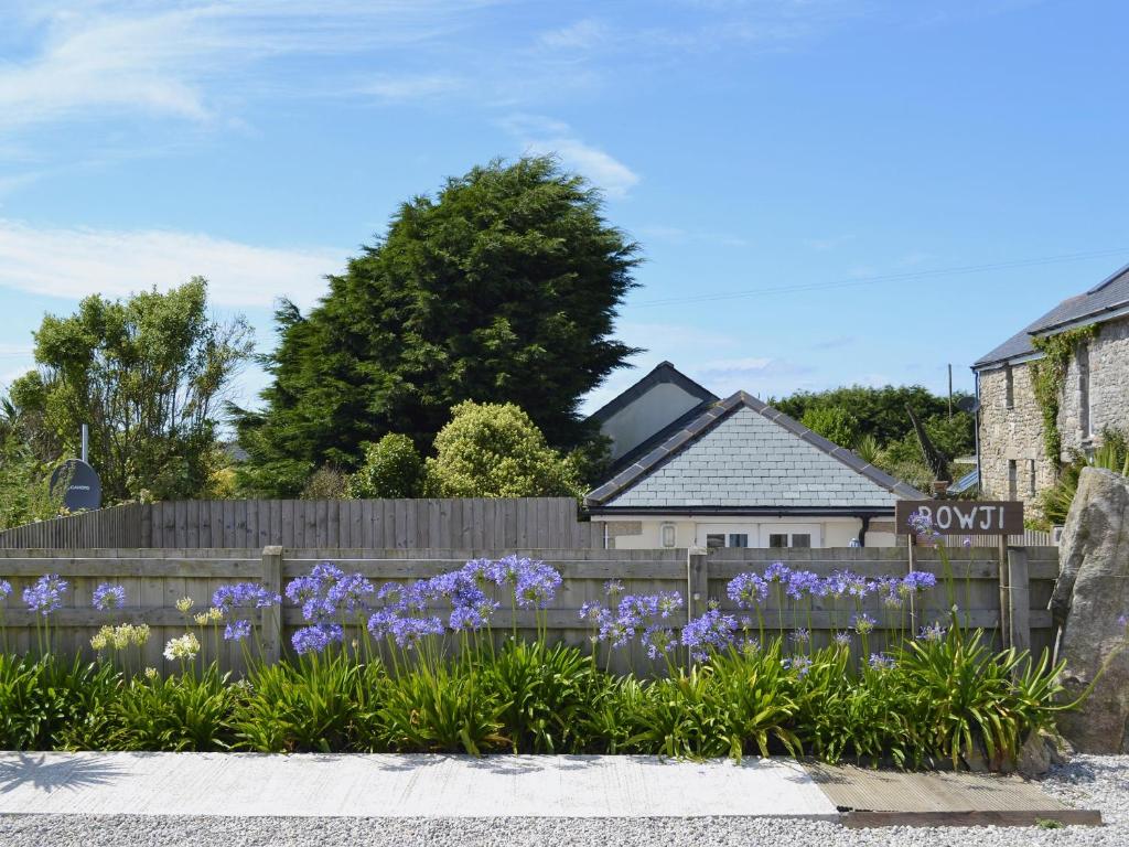 a fence with purple flowers in front of a house at Bowji in St. Just