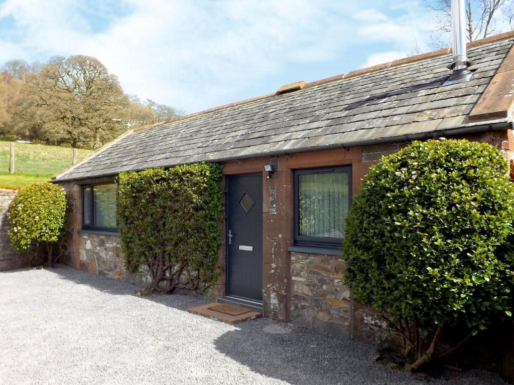 a small stone house with a black door at Wee Glebe in Moniaive