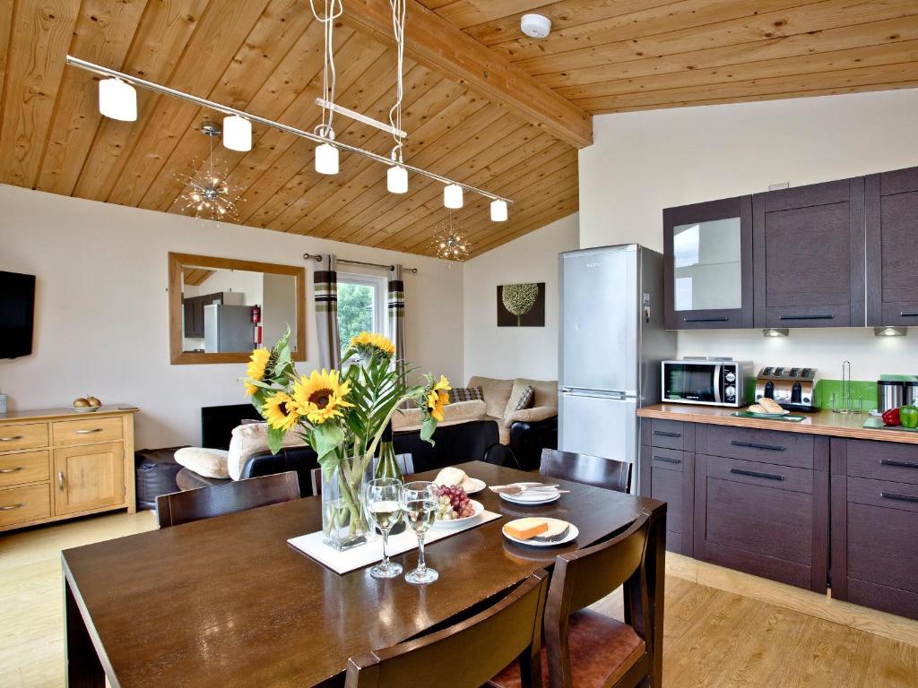a kitchen and living room with a wooden ceiling at Garfield Lodge in Hawkchurch