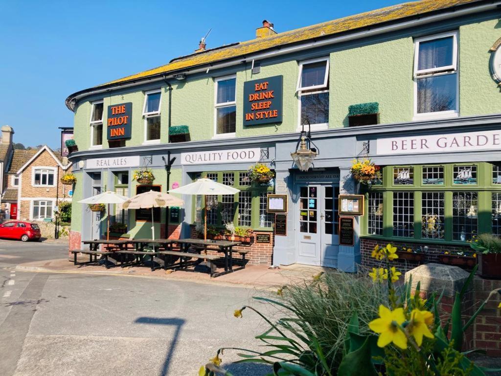 una taberna al aire libre con mesas y sombrillas frente a un edificio en The Pilot Inn en Eastbourne