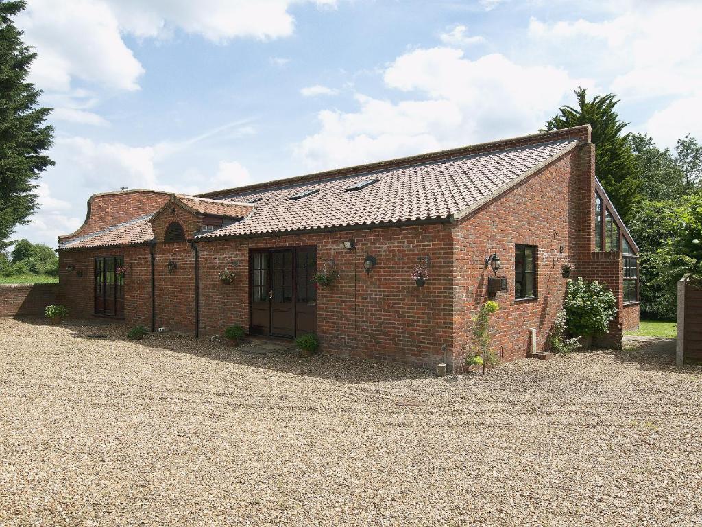 a brick building with a gravel driveway in front of it at St Andrews Barn in Necton