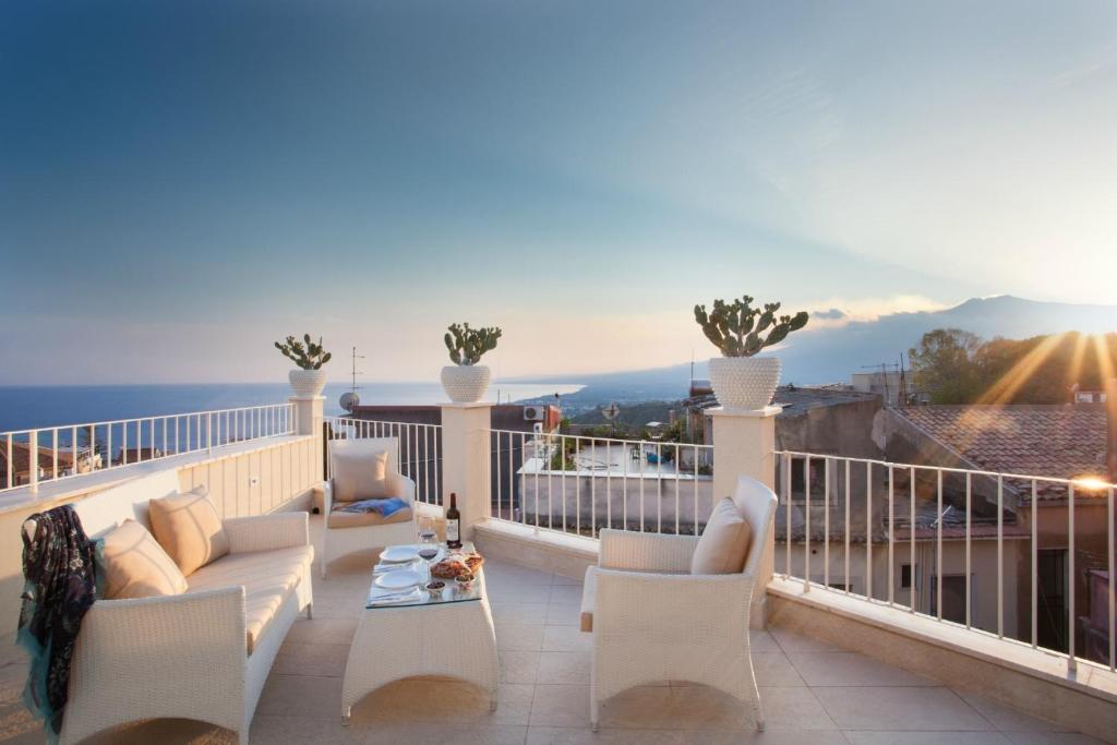 einen Balkon mit weißen Möbeln und Meerblick in der Unterkunft La Malandrina - Apartments & Suites in Taormina