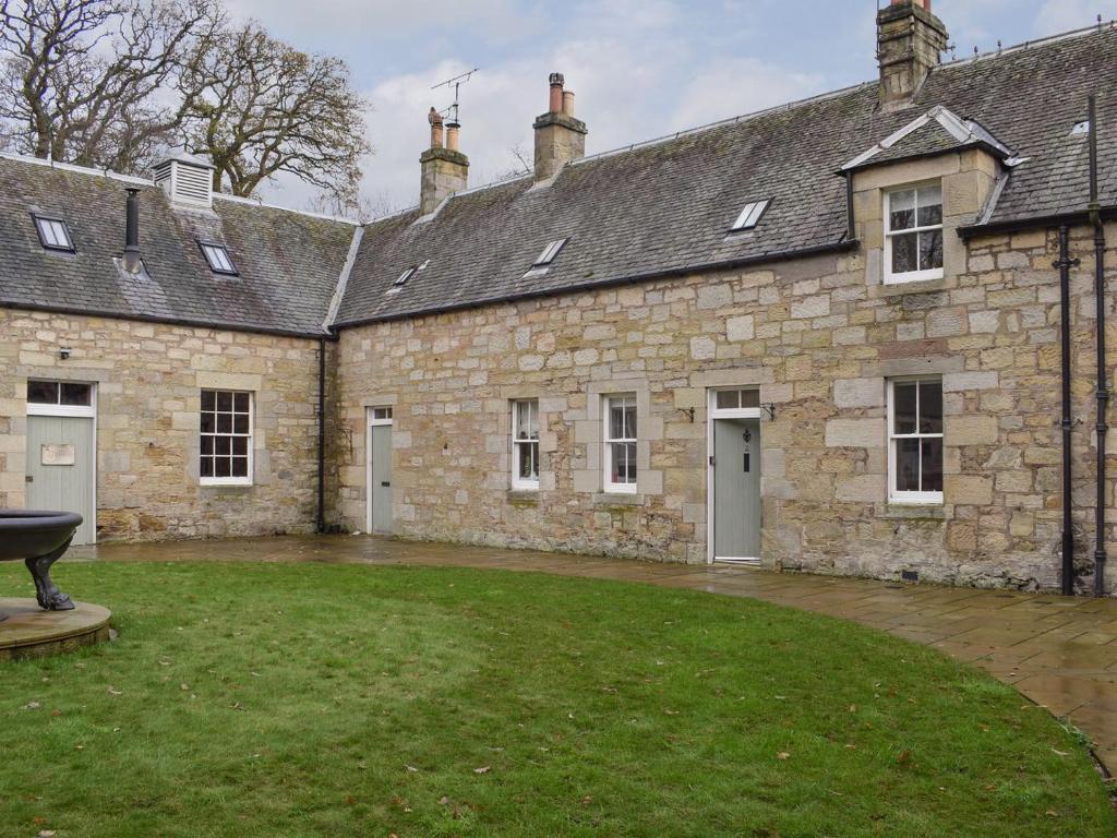 an external view of a stone building with a yard at Coachmans Cottage in Falkland