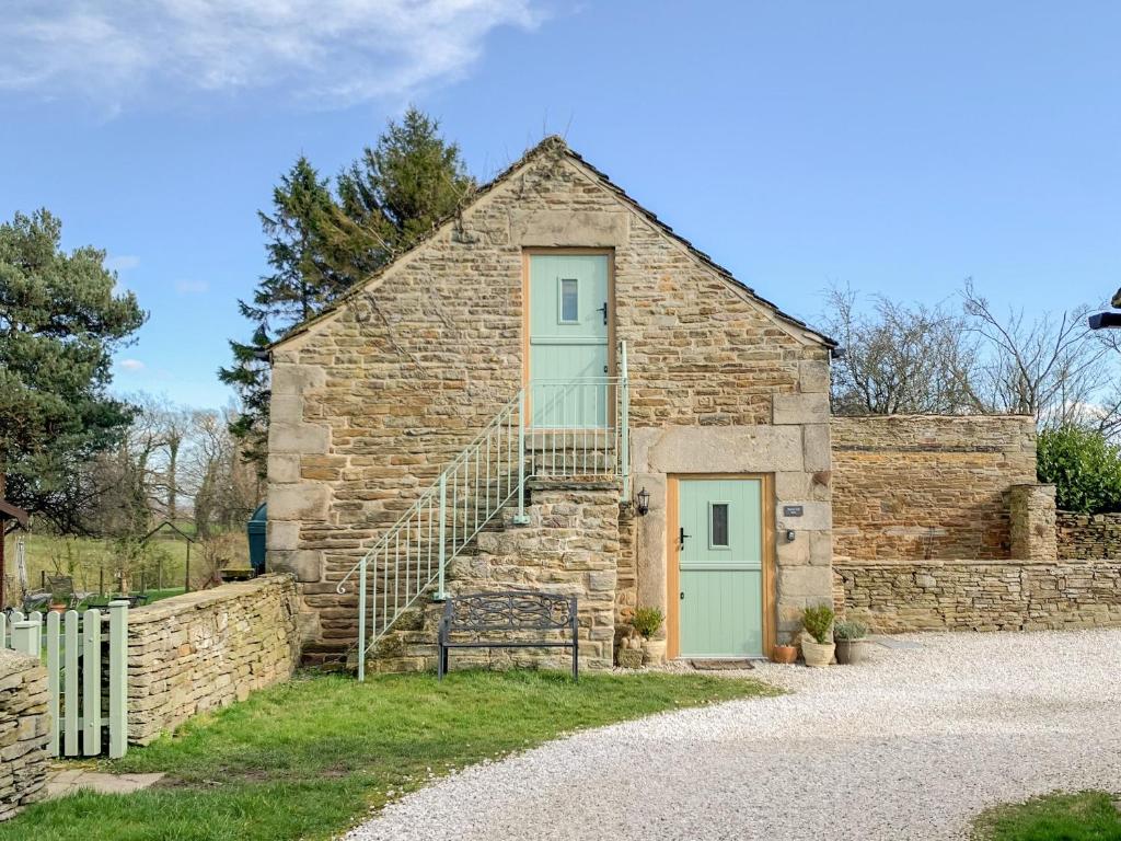 an old stone building with a green door and stairs at Tawny Owl Barn in Barlow