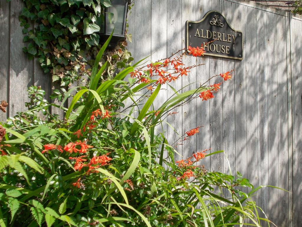 a sign on a fence with plants and flowers at Alderley House in Bourton on the Water