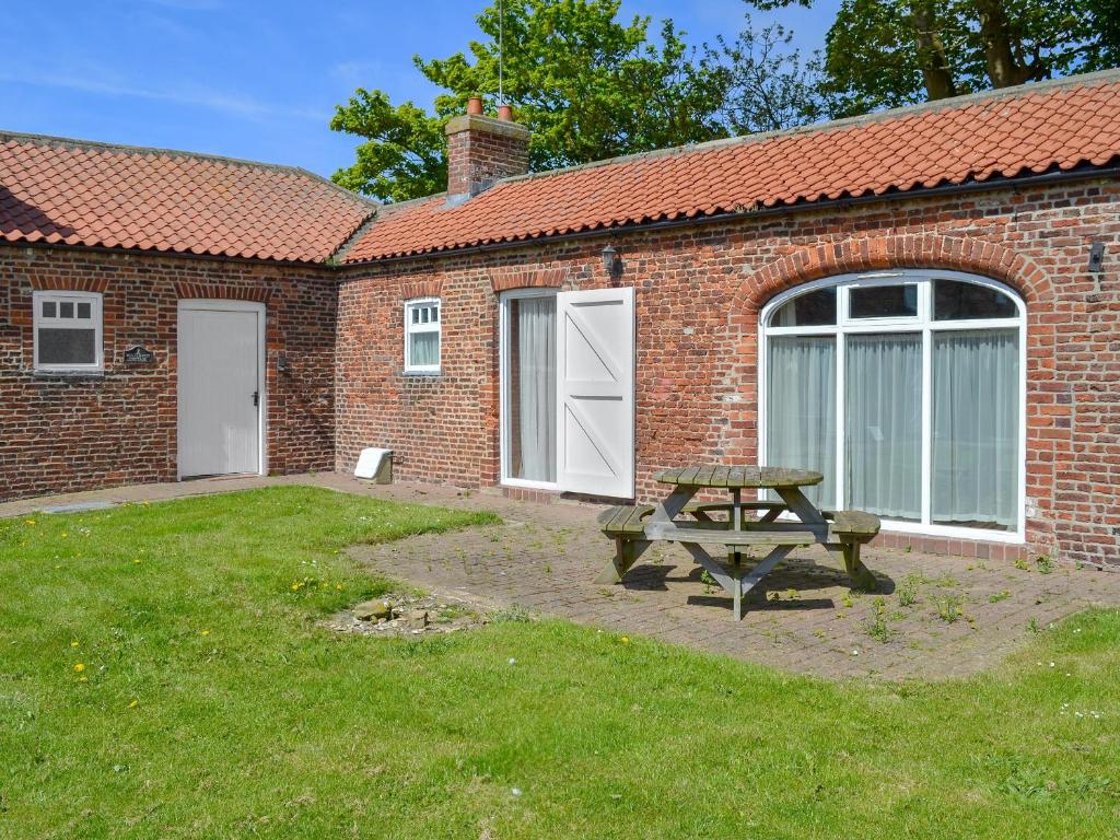 a picnic table in front of a brick building at Guillemot Cottage in Flamborough