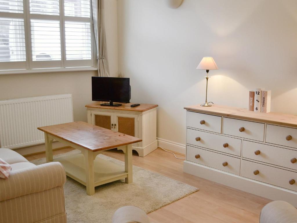 a living room with a tv and a table and a dresser at Percys Place in Alnwick