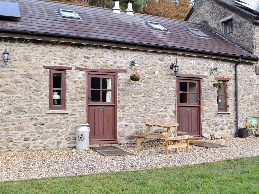 a stone cottage with a picnic table in front of it at The Pig Sty in Llanfair-ar-y-bryn