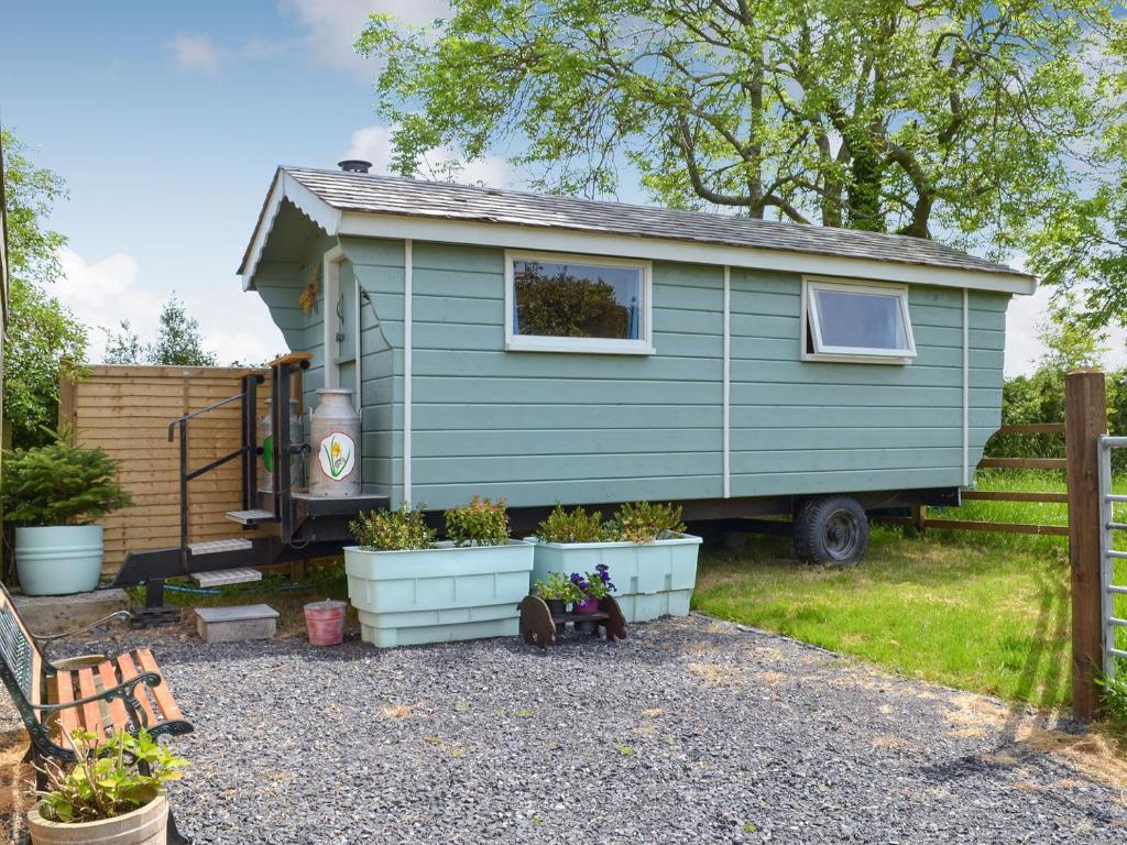 a green tiny house in a yard with plants at Shepherds Rest in Wedmore