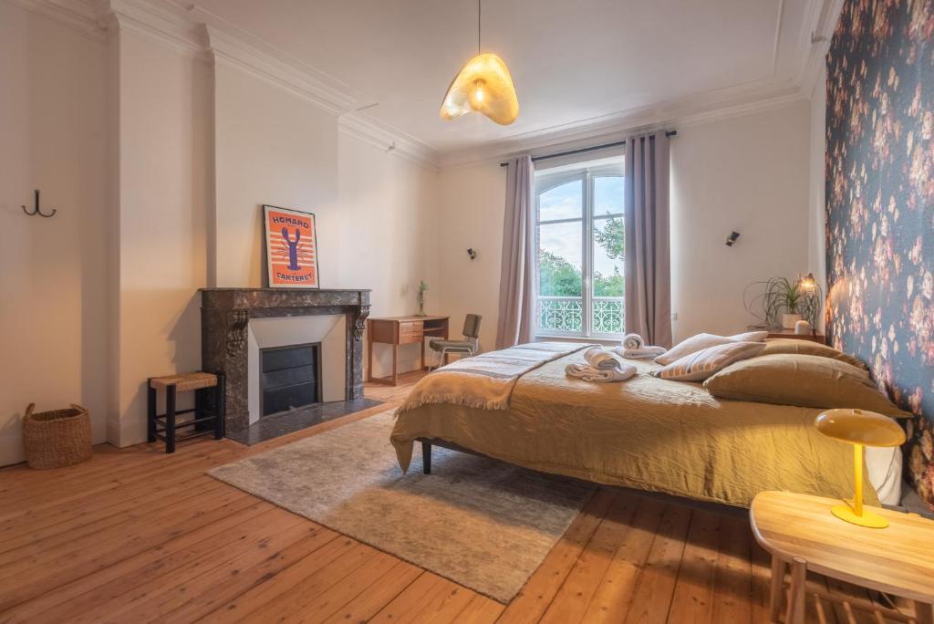 a bedroom with a large bed and a fireplace at La Villégiature in Coutances