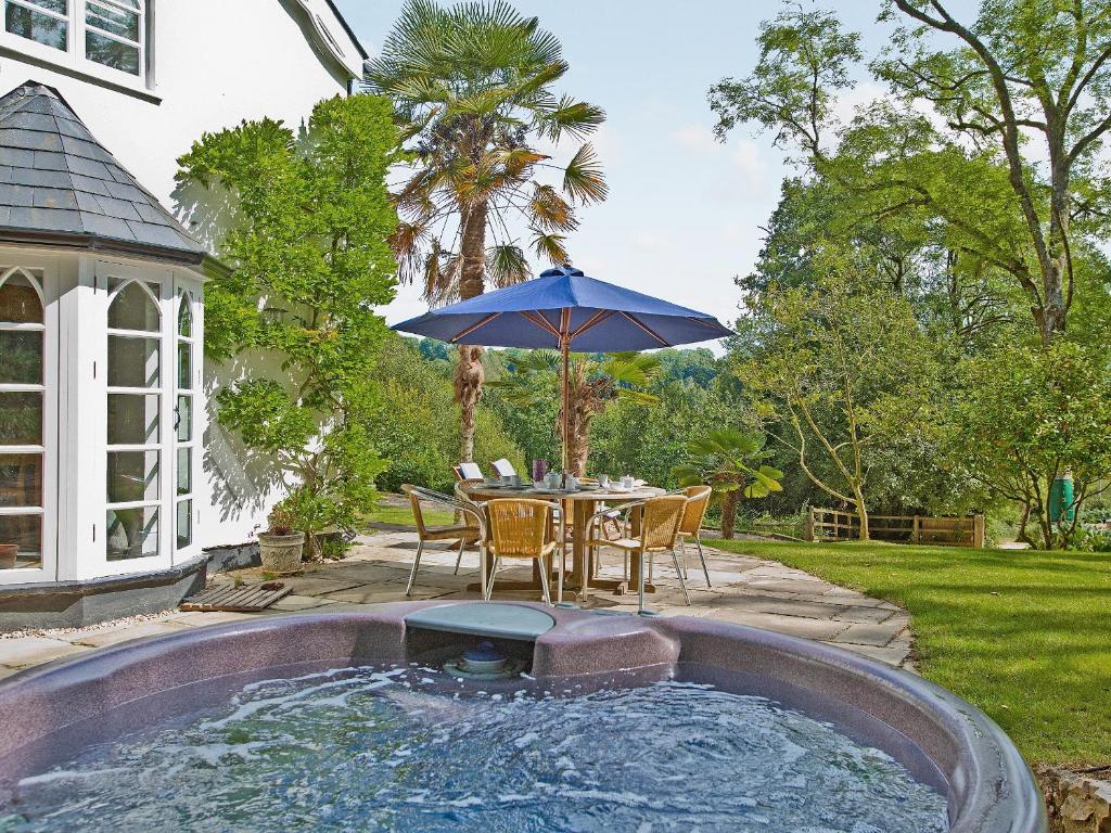 un patio con una mesa y una sombrilla en una piscina en Slowpool 