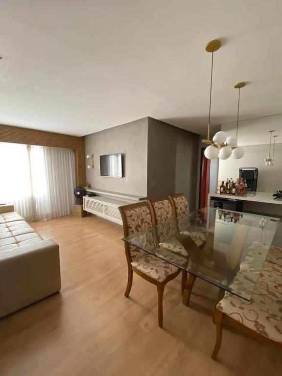 a living room with a glass table and chairs at ENCANTADOR , MODERNO E CONFORTÁVEL !!! in Belo Horizonte