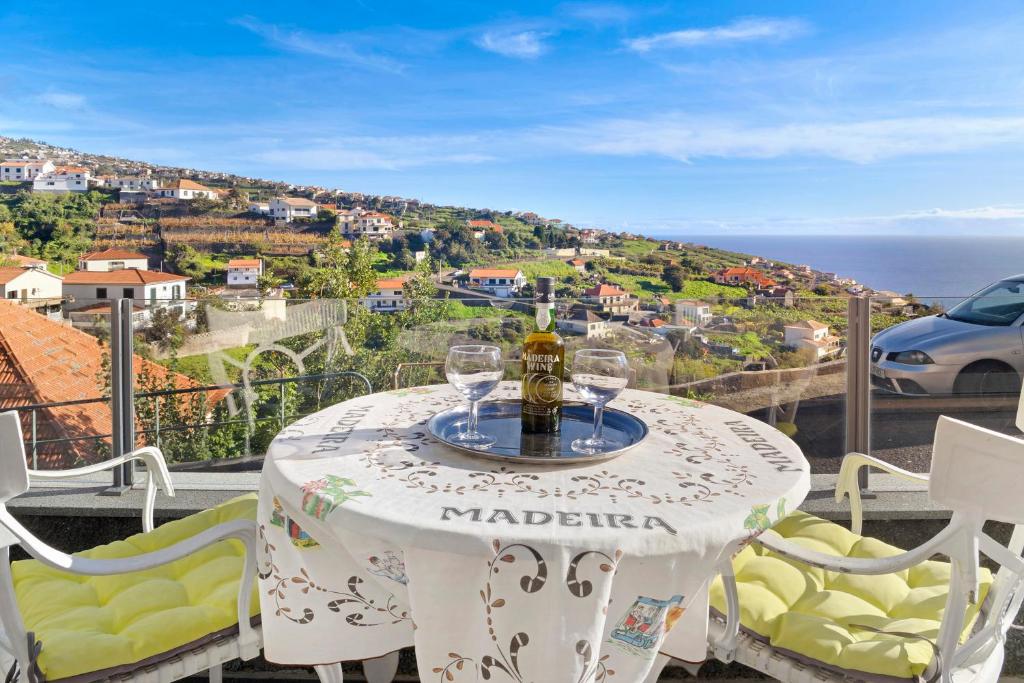 a table with a bottle and glasses on a balcony at Vila Morning Sun in Estreito da Calheta