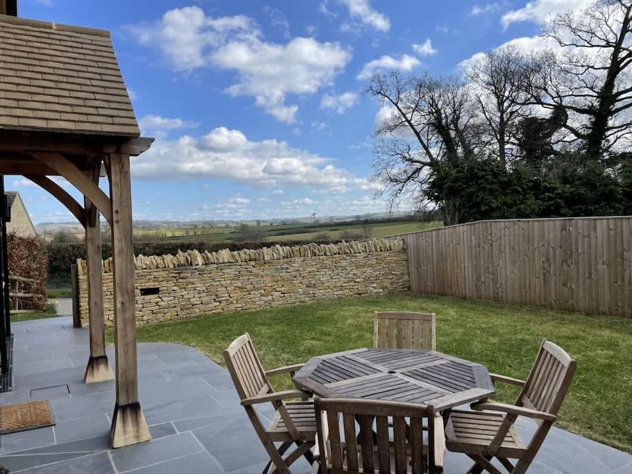a patio with a wooden gazebo and a table and chairs at Newly built house with elegant touches... in Todenham