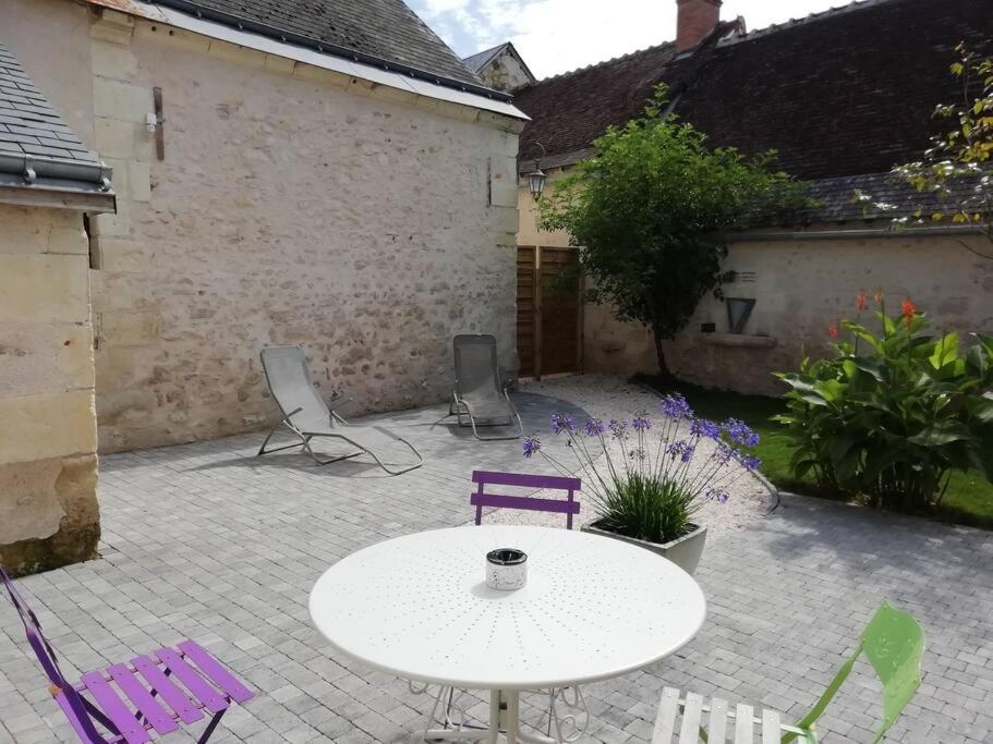 un patio con una mesa blanca y sillas moradas en Charmante maison de village en Val de Loire, en Rivarennes