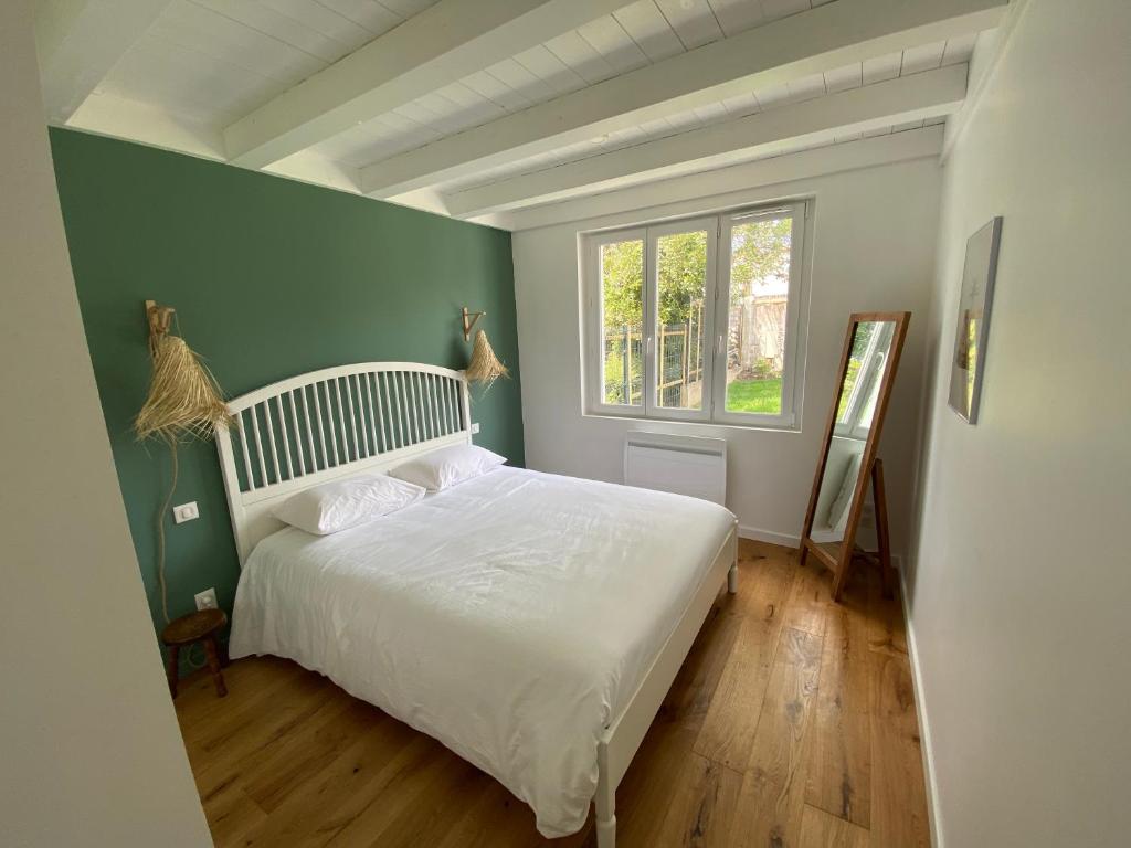 sypialnia z białym łóżkiem i zieloną ścianą w obiekcie Maisonnette confortable à Pornic w mieście Pornic