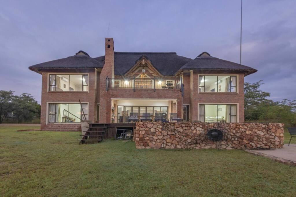 a large brick house with a stone wall at The Jasper House 73 in Mabula