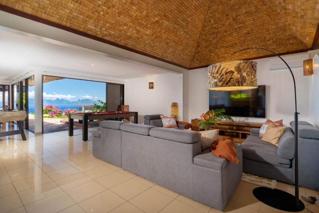 a living room with a couch and a television and a table at Magnificent 5 Br Villa with pool: amazing views in Punaauia
