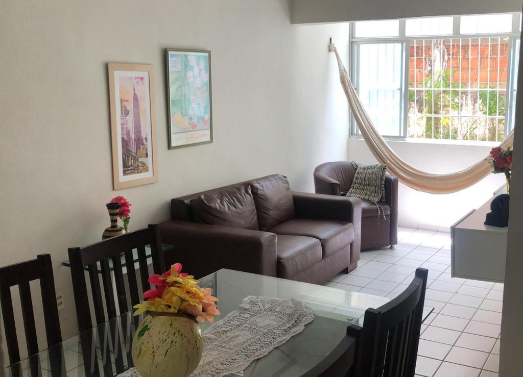 uma sala de estar com uma mesa e um sofá em Apt Candeias para 6 pessoas no Recife