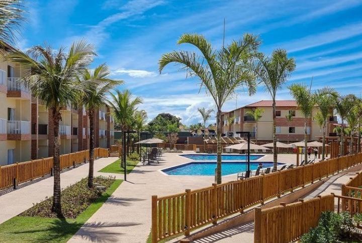 un complejo con piscina y palmeras en Resort Ondas Praia apart, en Porto Seguro