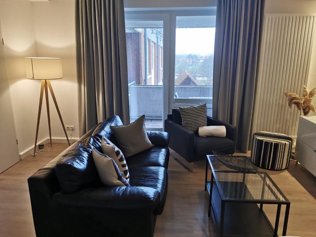 uma sala de estar com um sofá de couro preto e uma janela em FeWo Nordsee-Perle Meerblick - Horumersiel em Horumersiel