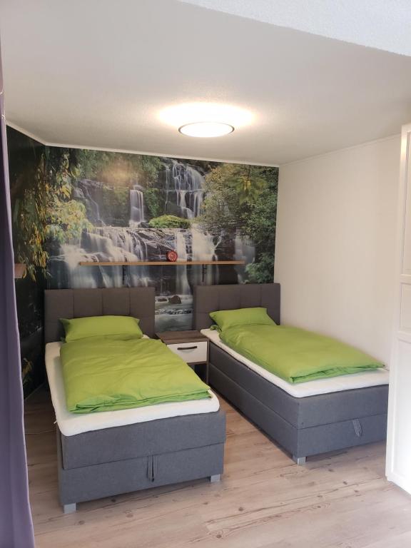 two beds in a room with a painting on the wall at Monteurzimmer in Malterdingen
